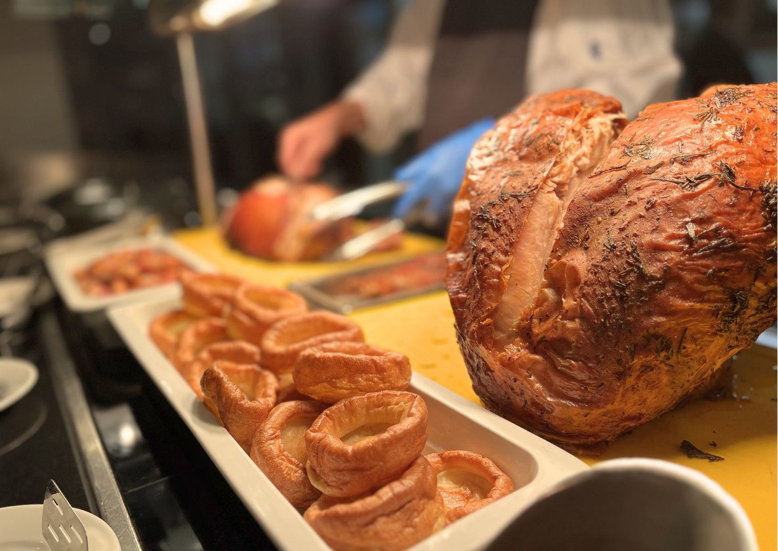 Roast turkey leg with herbs on a carving station, slices of meat and pastry spirals in the foreground.