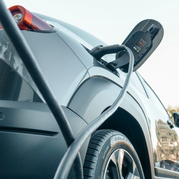 Electric car being charged with a cable plugged into its side charging port outside in a parking area