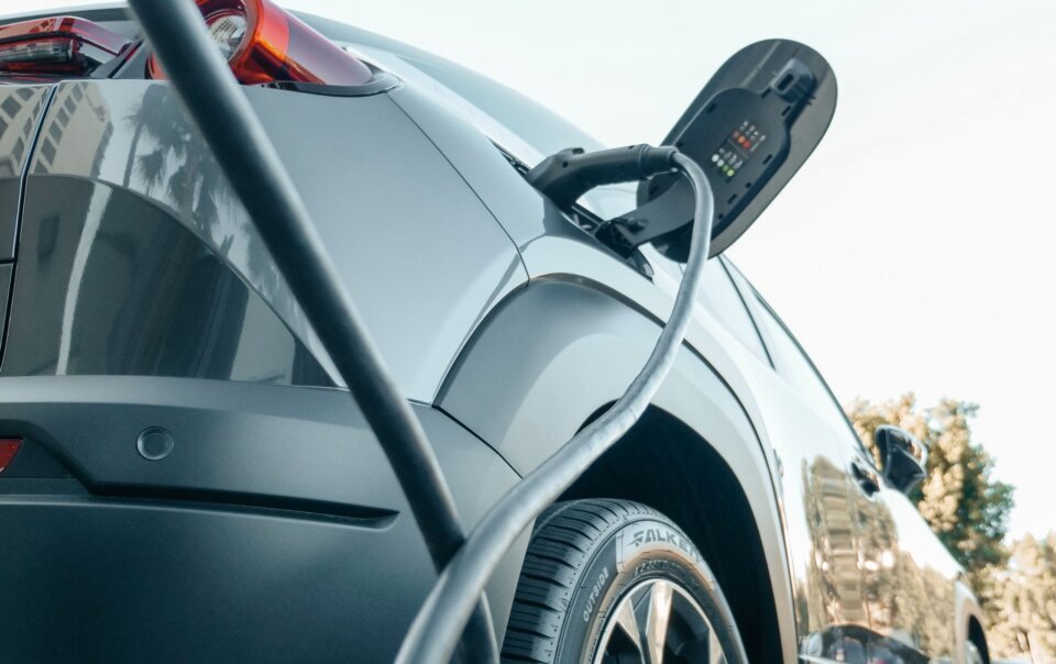 Electric car being charged with a cable plugged into its side charging port outside in a parking area